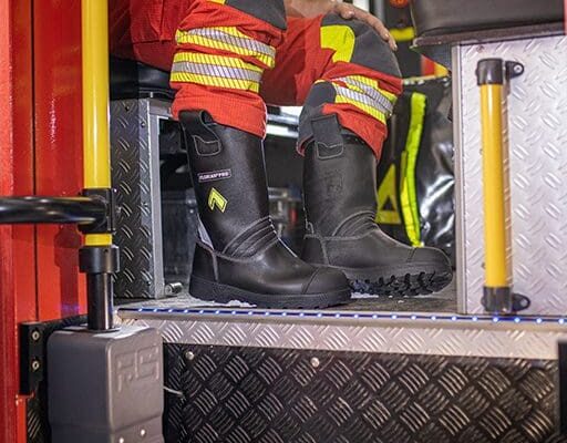 Ein Feuerwehrmann sitzt in einem Feuerwehrauto und Trägt Sicherheitsschuhe für den Rettungsdienst.
