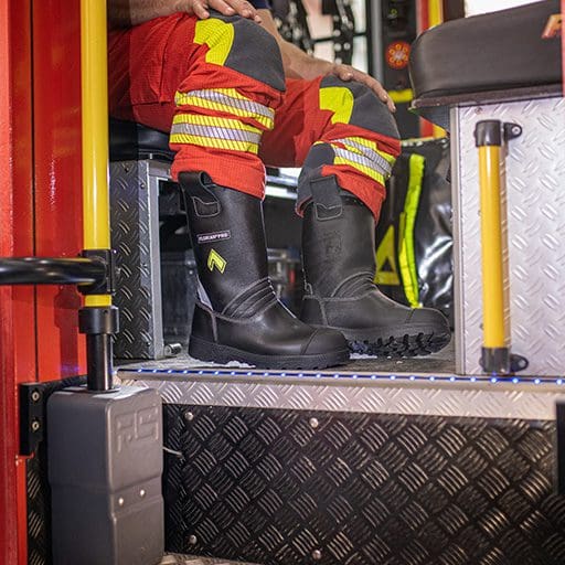 Ein Feuerwehrmann sitzt in einem Feuerwehrauto und Trägt Sicherheitsschuhe für den Rettungsdienst.